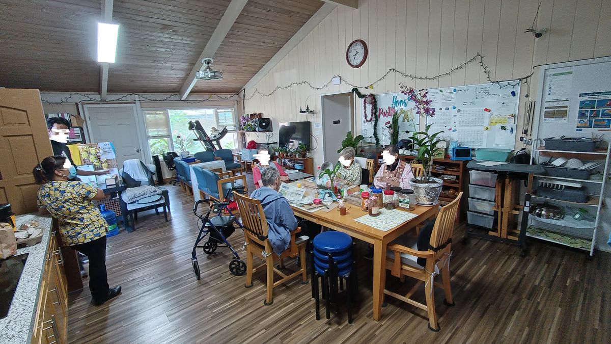 A cozy living space with people gathered around a dining table engaged in activities.
