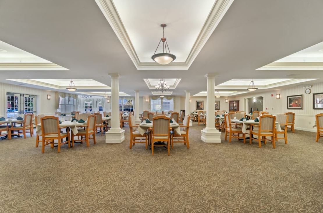 A spacious dining room with elegant lighting and wooden furniture.