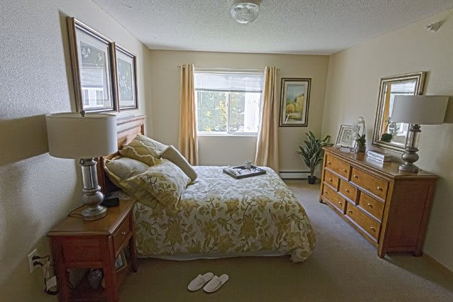 A cozy bedroom with a bed, dresser, and window letting in natural light.