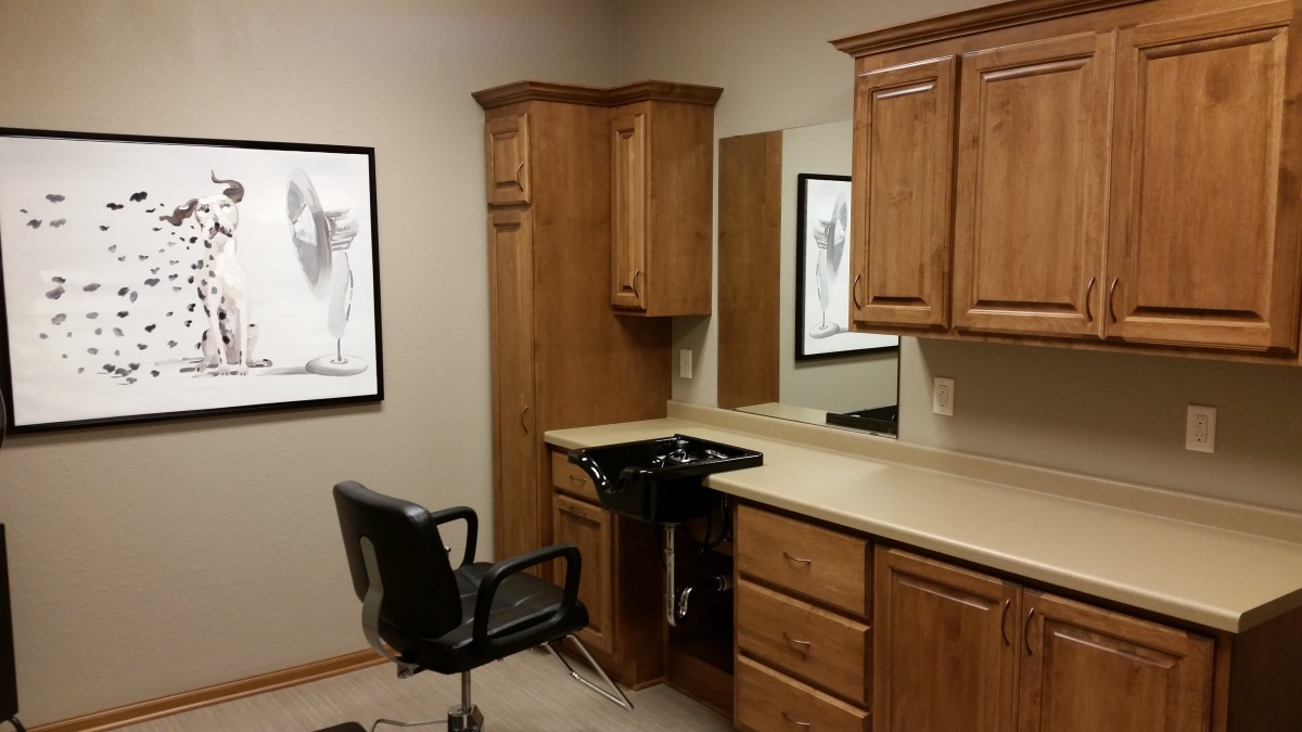 A cozy hair salon setup with a barber chair and wooden cabinetry.