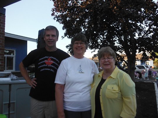 A group of three people posing for a photo outdoors in casual clothing.