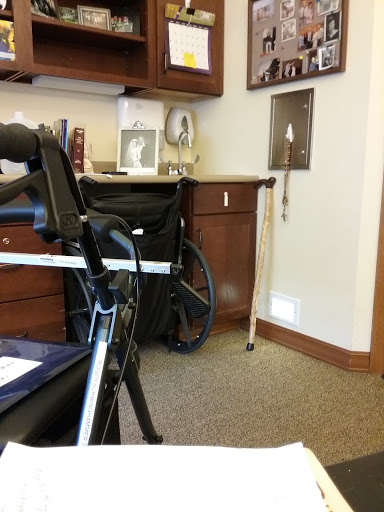 A cozy office space featuring a wheelchair and various furnishings.