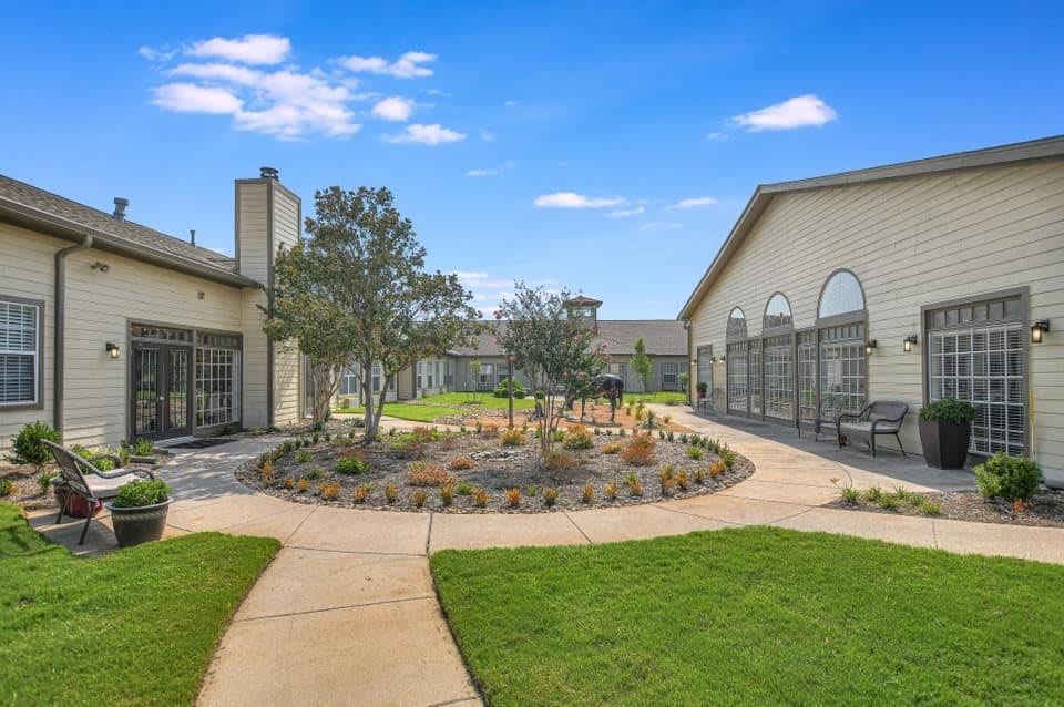A landscaped courtyard with pathways and greenery between buildings under a clear blue sky.