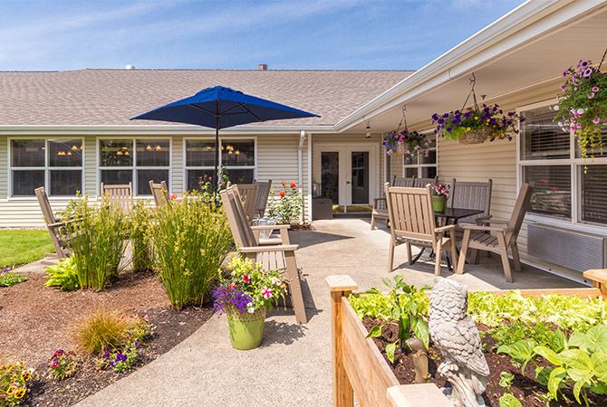A sunny patio with outdoor seating, plants, and a blue umbrella.