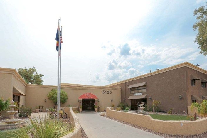 A building entrance with flags and a cloudy sky.