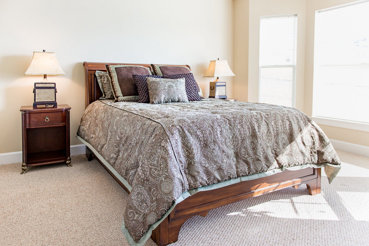 A well-appointed bedroom with a neatly made bed, decorative pillows, and a bedside lamp.