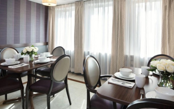 A well-lit dining room with elegantly set tables and comfortable chairs.