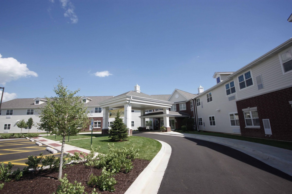 A modern residential building with a landscaped driveway and clear blue skies.