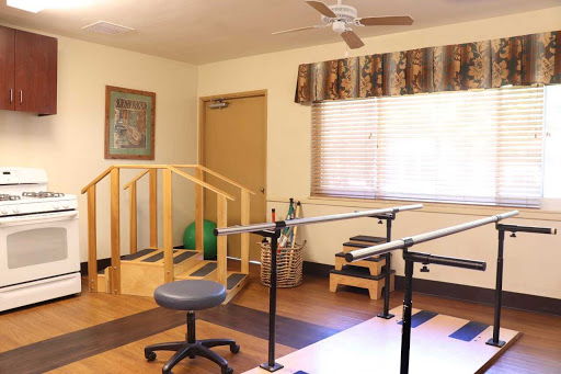 A physical therapy room equipped with exercise bars, a chair, and rehabilitation tools.
