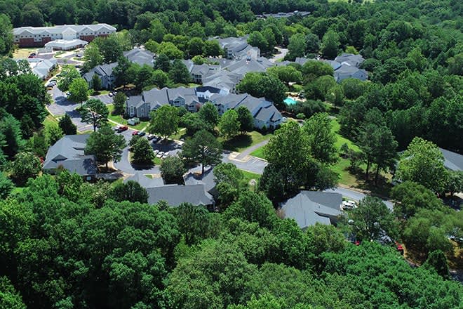 Aerial view of a lush residential neighborhood with houses surrounded by trees.