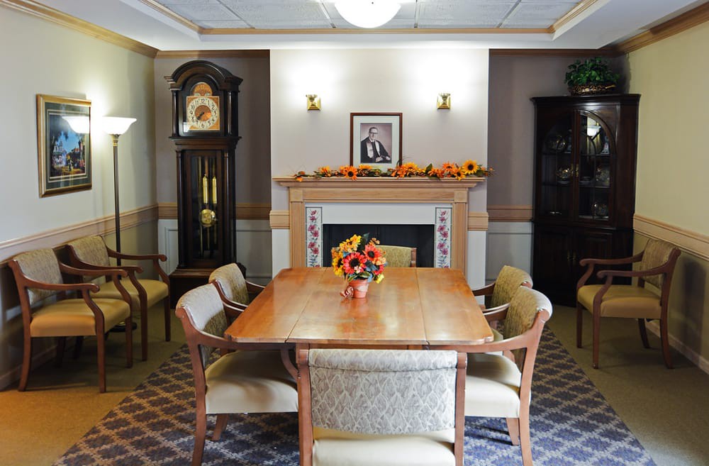 A well-appointed dining room with a wooden table, surrounded by chairs and featuring a fireplace adorned with seasonal decorations.