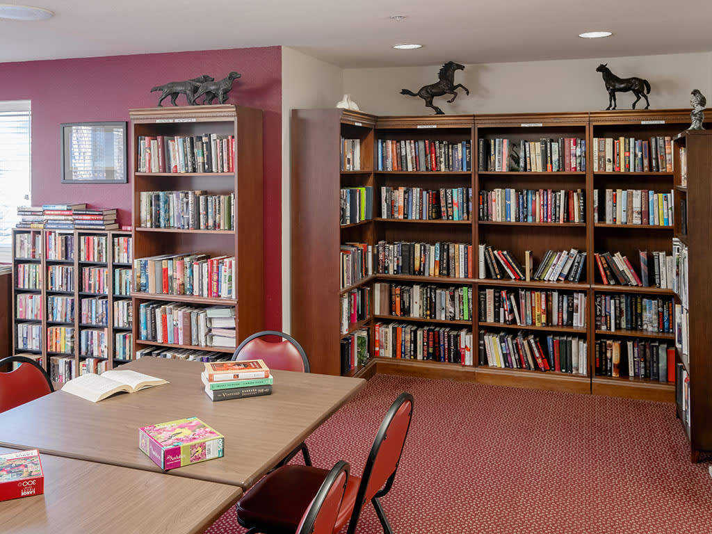 A cozy library corner with tables, chairs, and rows of bookshelves filled with books.