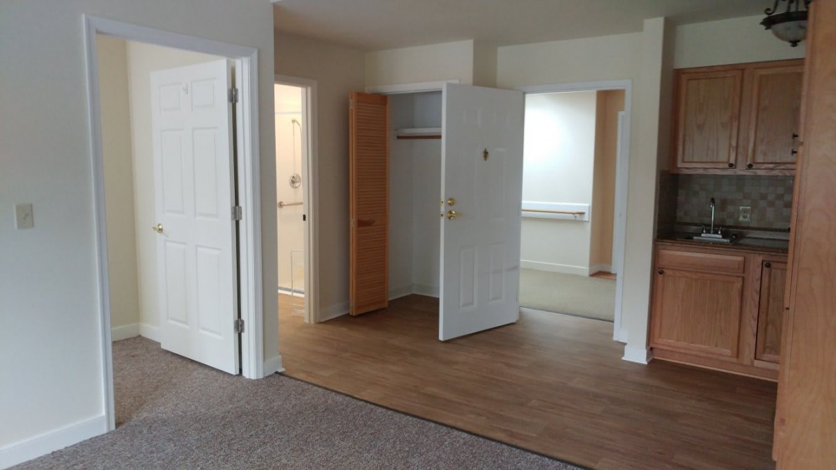 An empty apartment interior with open doors leading to different rooms and a closet.
