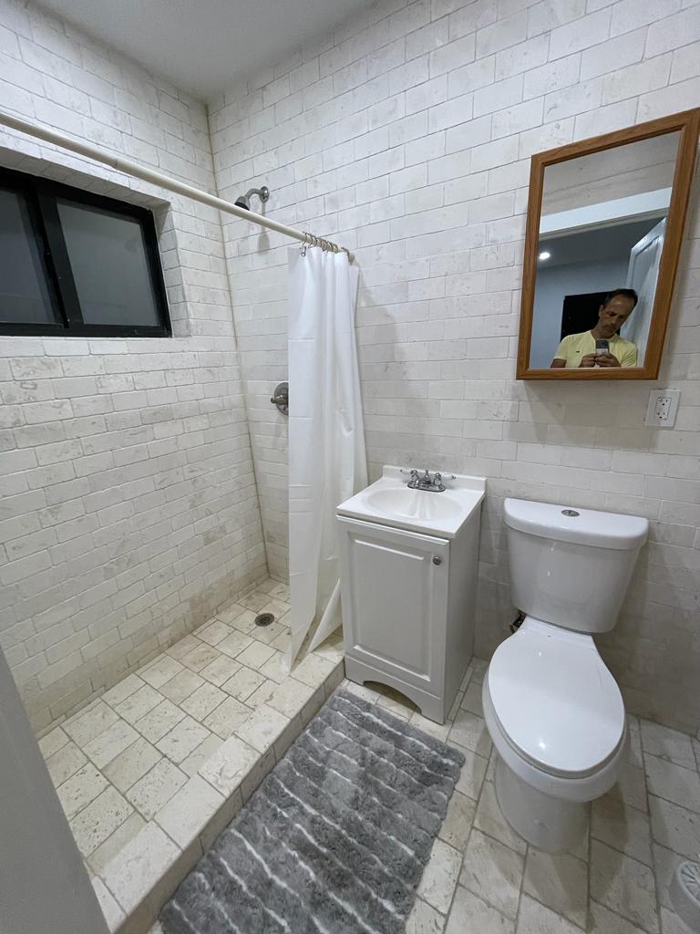 A small, modern bathroom with a shower, sink, and toilet.