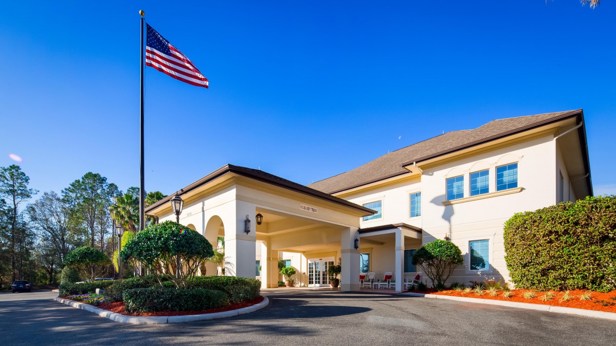 A hotel entrance with an American flag and clear blue sky in the background.