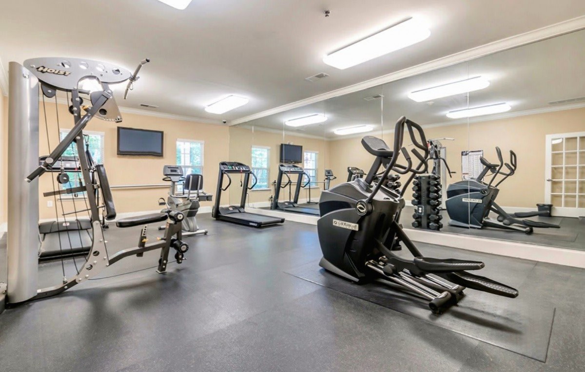 A well-equipped gym with treadmills, an elliptical machine, and weightlifting equipment.