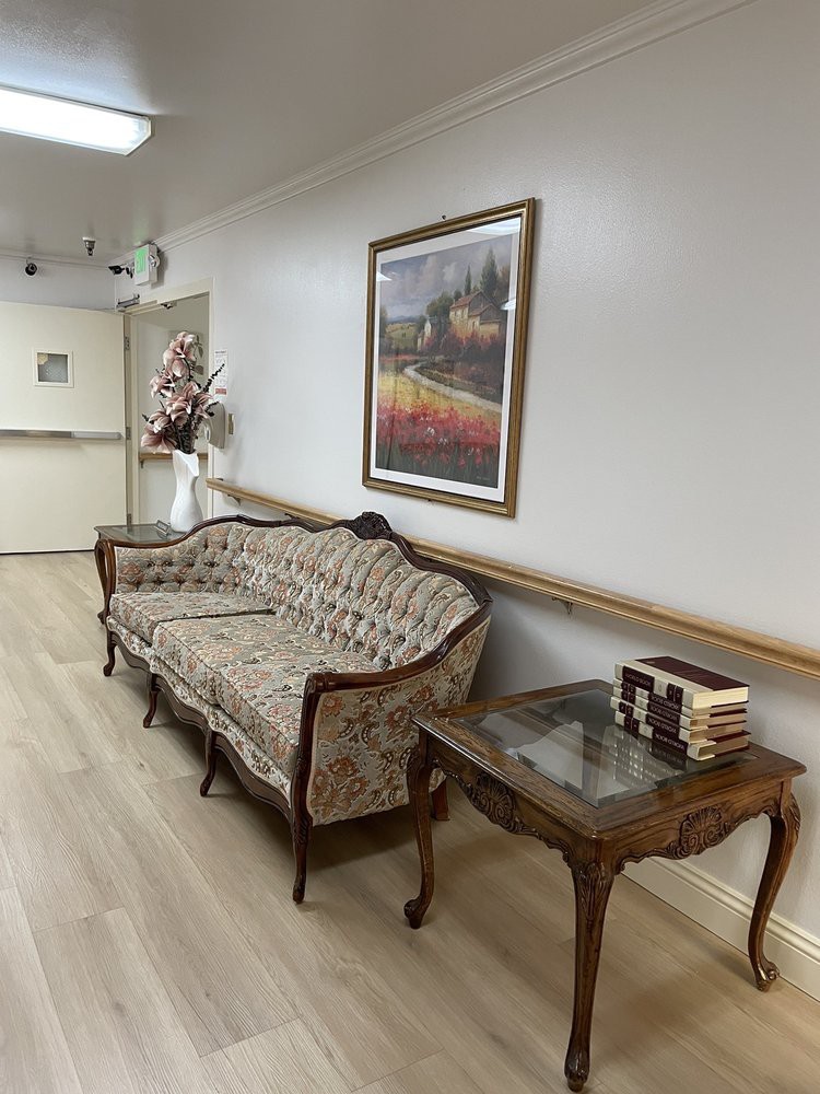 A hallway with a classic sofa and table, adorned with books and a painting on the wall.