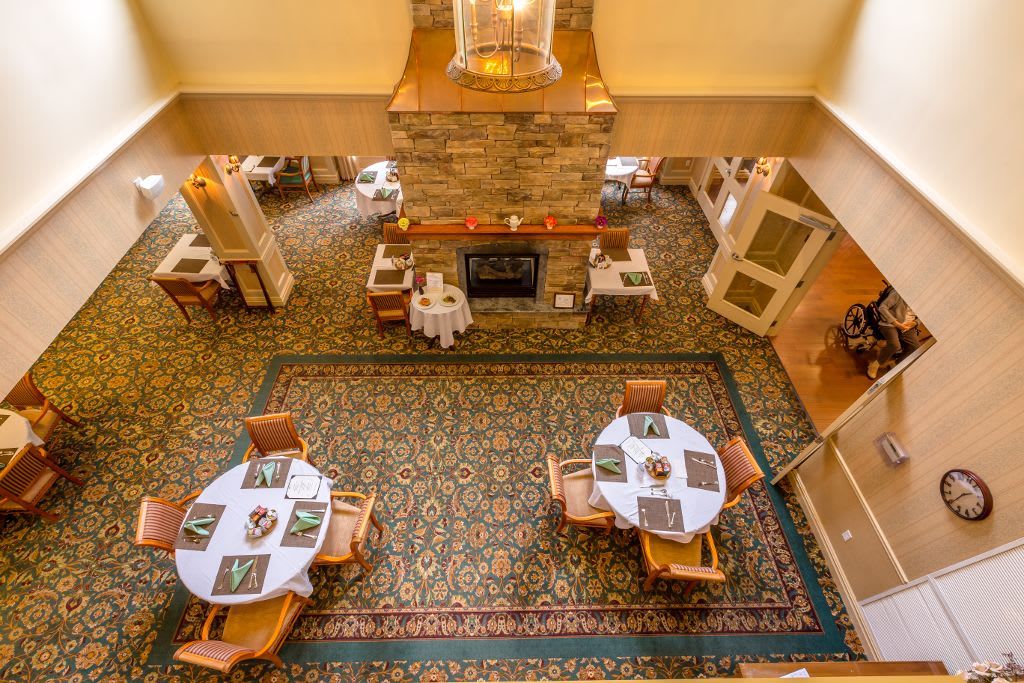 A cozy dining area with elegantly set tables and a large decorative carpet.