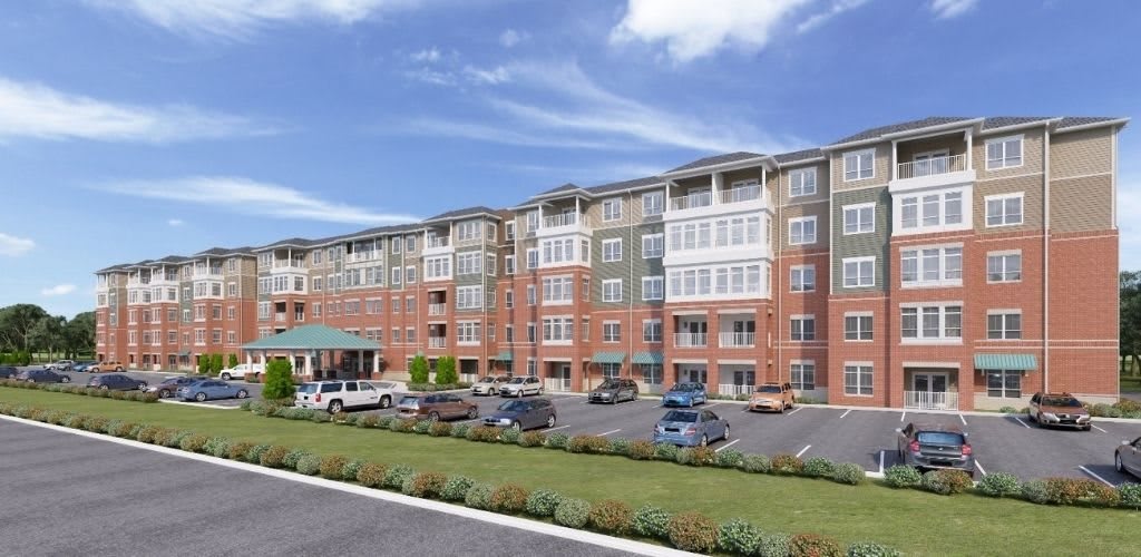 A modern multi-story apartment building with a parking lot in front.