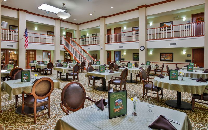 A spacious dining area with elegantly set tables and chairs, featuring a multi-level interior design.