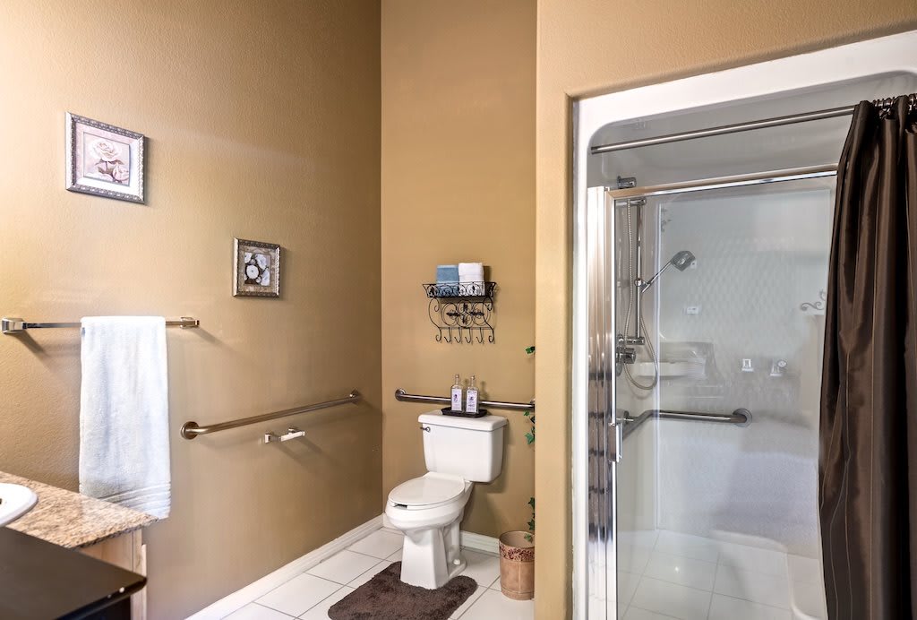 A modern bathroom featuring beige walls, a toilet, and a glass-enclosed shower.