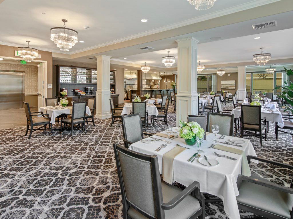 An elegant dining area with neatly arranged tables and chairs, featuring chandeliers and stylish decor.
