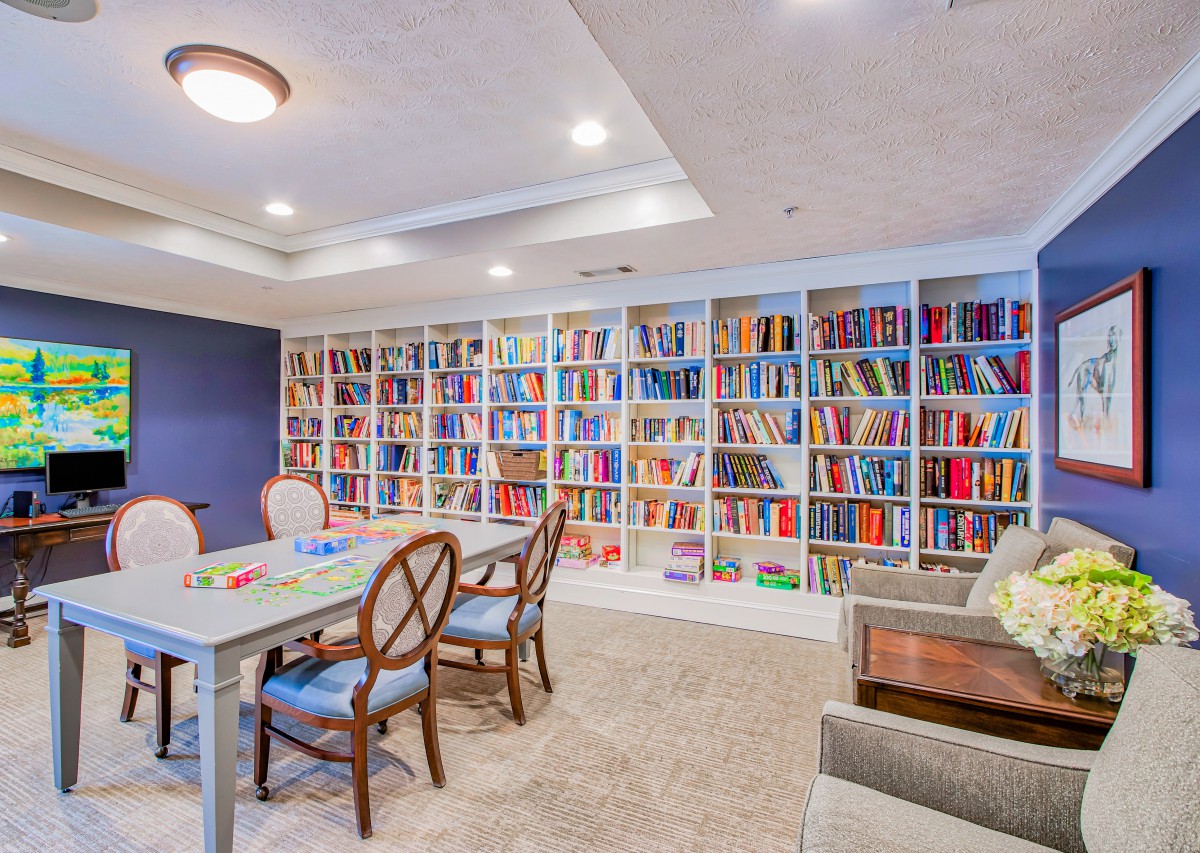 A cozy library room with bookshelves lining the wall, featuring a table and chairs for reading or studying.