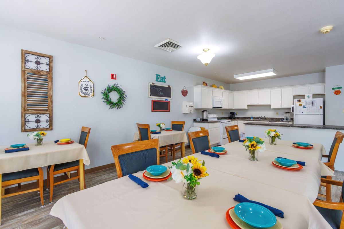 A bright dining area with neatly set tables, colorful plates, and floral decorations.