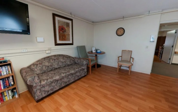A cozy living space featuring a couch, two chairs, a small table, and wall art.