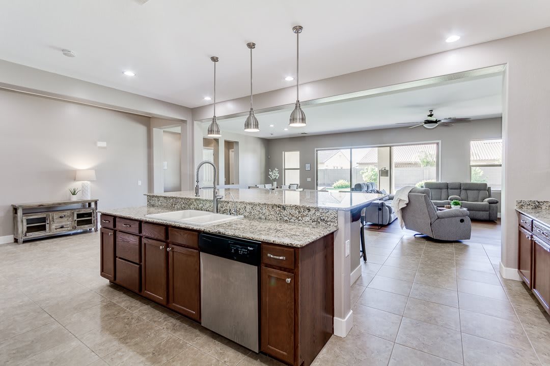 A modern open-concept kitchen with an island, featuring granite countertops, pendant lighting, and stainless steel appliances.