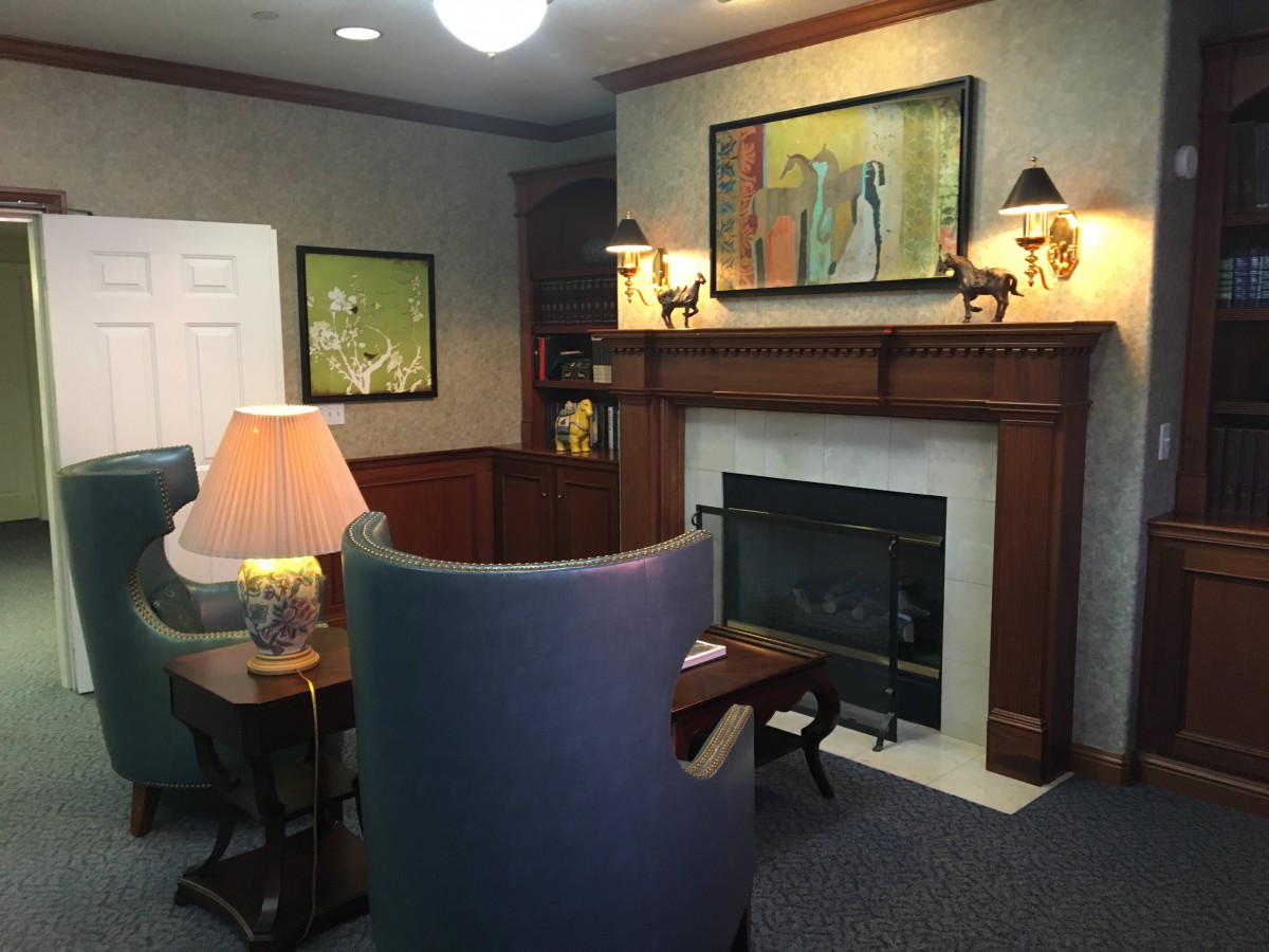 A cozy living room featuring a fireplace, artwork, and comfortable seating.