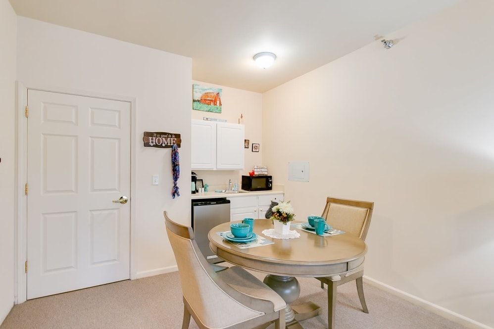 A cozy dining area with a round table and chairs, adjacent to a small kitchen.