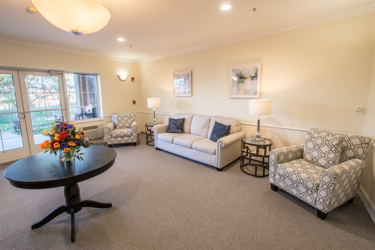 A cozy living room with comfortable sofas and armchairs, decorated with framed artwork and ambient lighting.