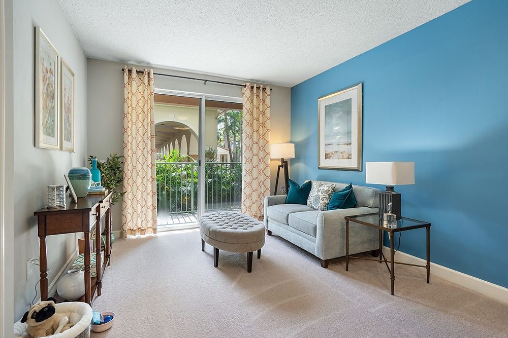 A stylish living room with a blue accent wall, modern furniture, and bright natural light.