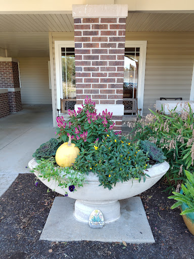 A charming outdoor planter filled with colorful flowers and a decorative pumpkin.