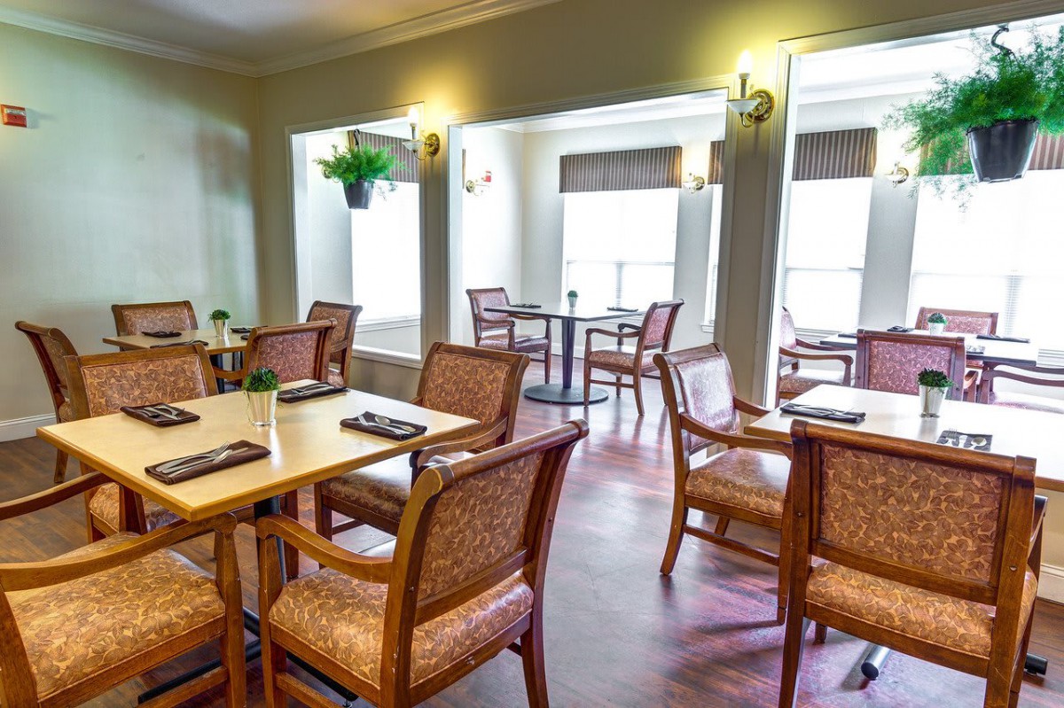A cozy dining room with neatly arranged tables and chairs, bathed in natural light.