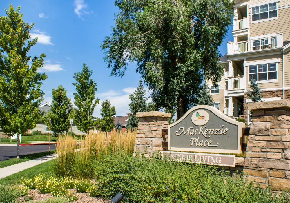 Entrance sign to a residential apartment complex surrounded by well-maintained landscaping and trees.