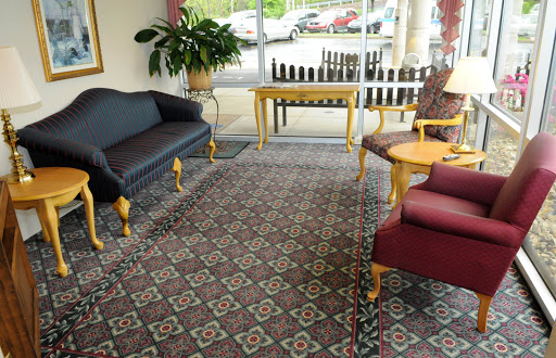 A cozy lobby area featuring a couple of sofas, a chair, and a coffee table, illuminated by natural light.