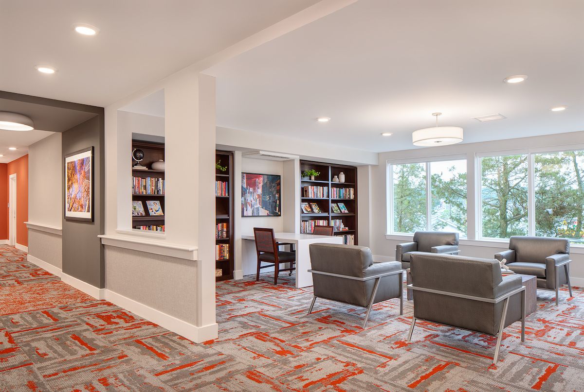 A modern living room with comfortable seating, bookshelves, and large windows.