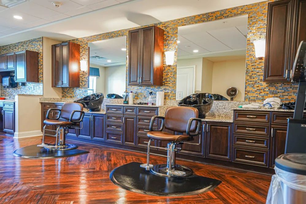 A luxurious salon interior with barber chairs, large mirrors, and stylish cabinetry.