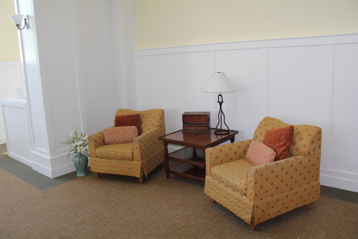 A cozy living room setting with two armchairs, a side table, and a lamp.