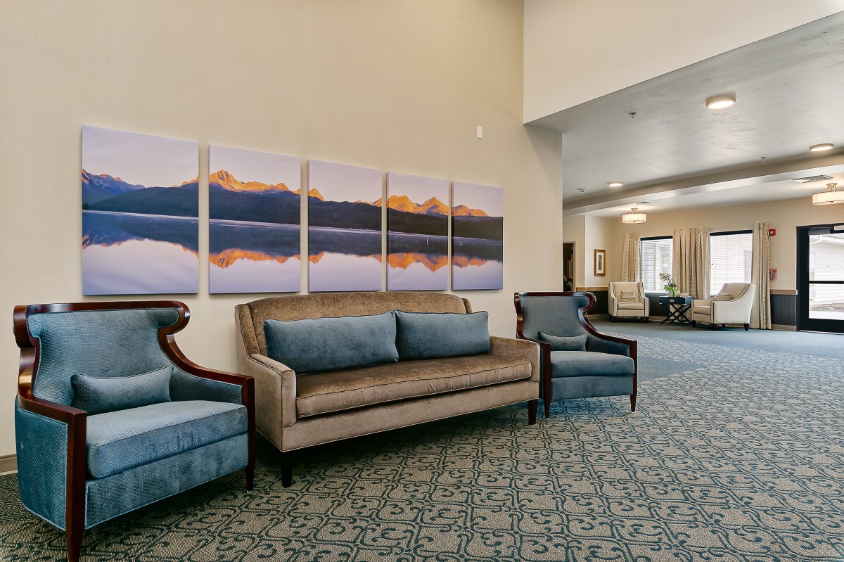 A spacious lobby area featuring comfortable sofas and chairs with scenic artwork on the wall.