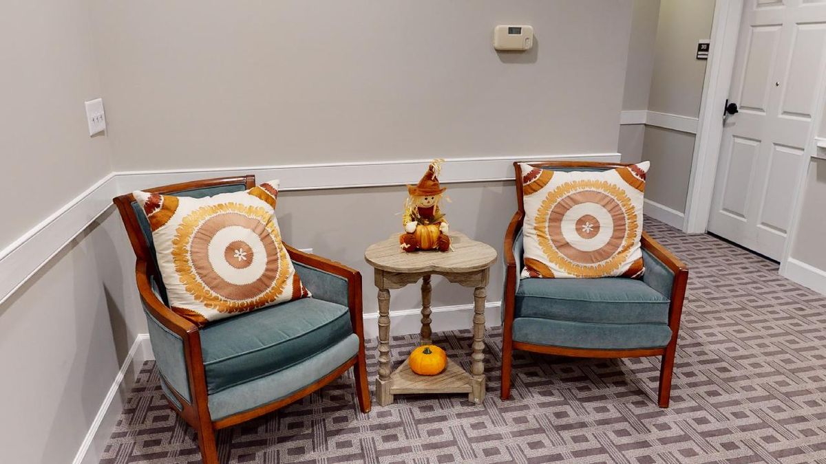 A cozy seating area with two chairs, decorative pillows, and autumn-themed decorations on a small table.