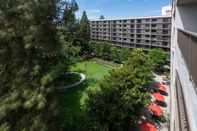 A view of a hotel building surrounded by lush gardens and trees.