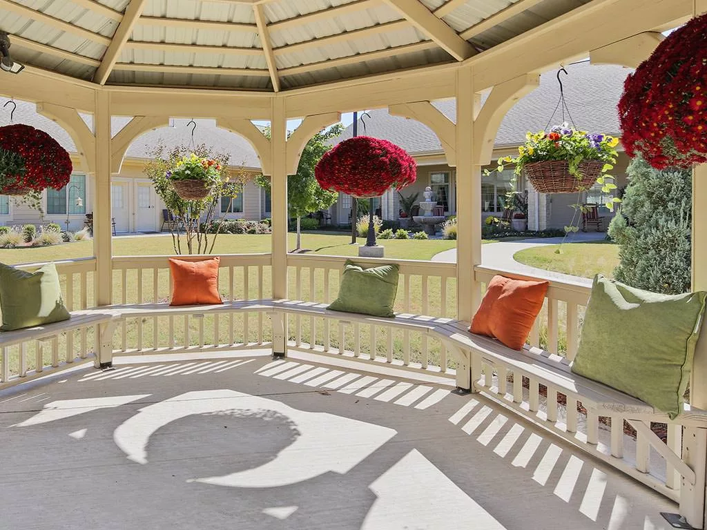 A cozy gazebo with colorful cushions and hanging plants, providing a shaded spot in the garden.