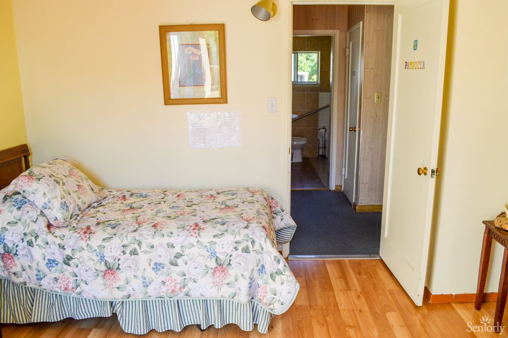 A cozy bedroom with a floral quilt on the bed and an open doorway leading to another room.