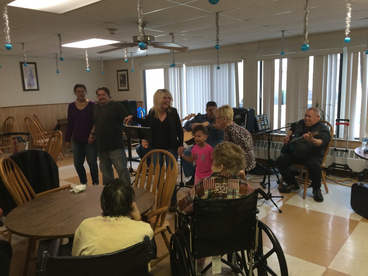 A group of people gathered in a nursing home, engaging in a community activity.