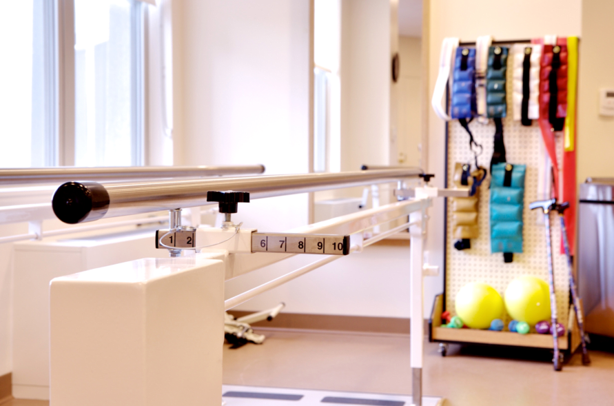 A physical therapy room equipped with parallel bars and rehabilitation tools.