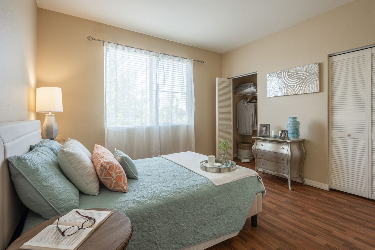 A cozy and bright bedroom with minimalistic decor and a large window letting in natural light.