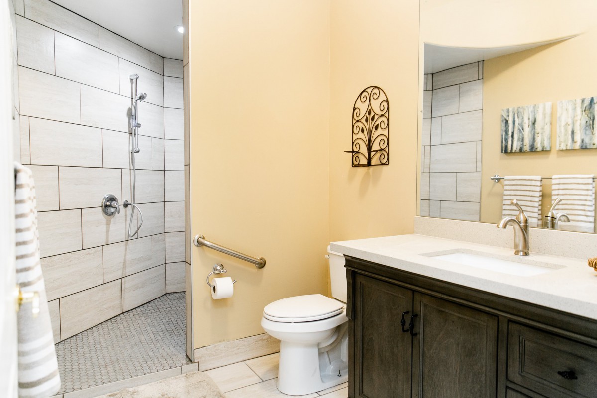 A modern bathroom with a toilet, sink, and accessible shower area.